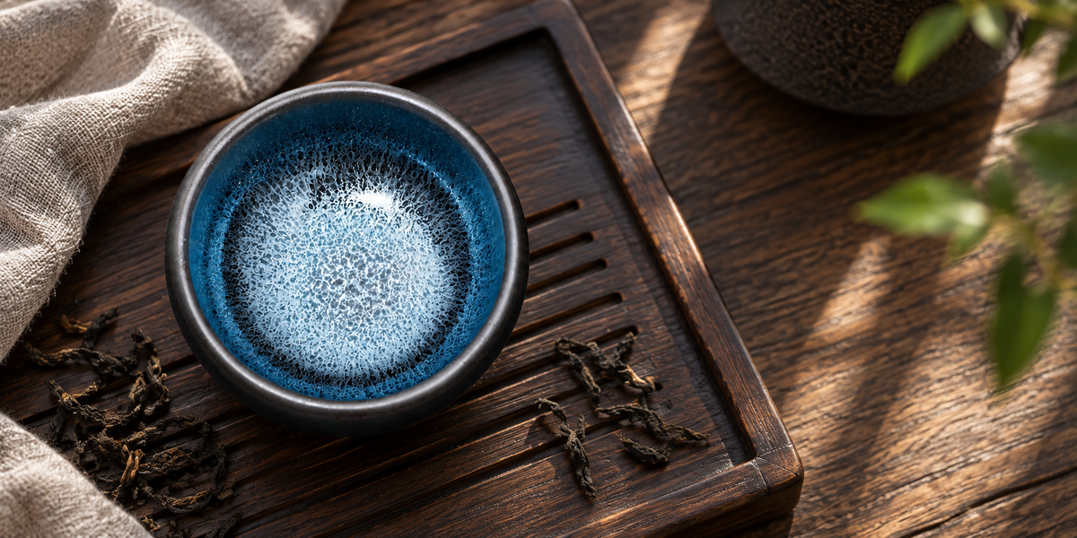 Blue Kirin Zen Jianzhan Teacup on a wooden tea tray with linen and tea leaves