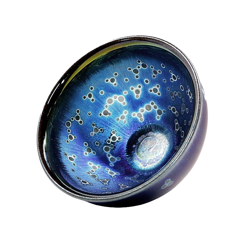 A circular ceramic tea cup with a blue color and a pattern of white dots or stars on the surface.