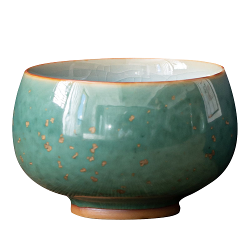 A ceramic tea cup with a green and blue glaze, showing a smooth rim and a textured surface.