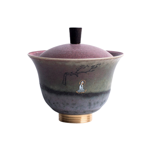 A round ceramic coffee cup with a purple and green color pattern and a gold-colored handle, featuring a tree and moon graphic on the side.