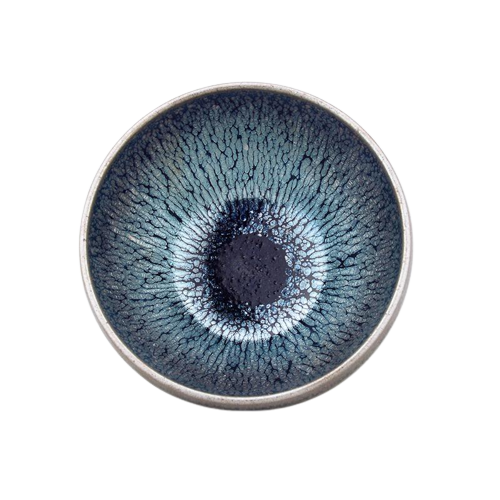 A circular ceramic teacup with a blue and black speckled pattern in the center, resembling an eye, with a metallic rim.
