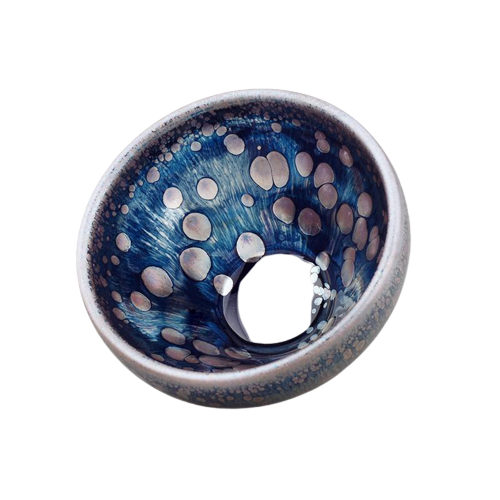 A round ceramic teacup with a blue and white dotted pattern and a metallic ring at the bottom.