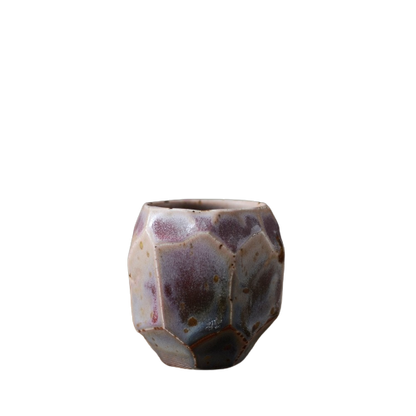 A ceramic tea cup with a textured, speckled surface featuring a mix of purple and brown colors.