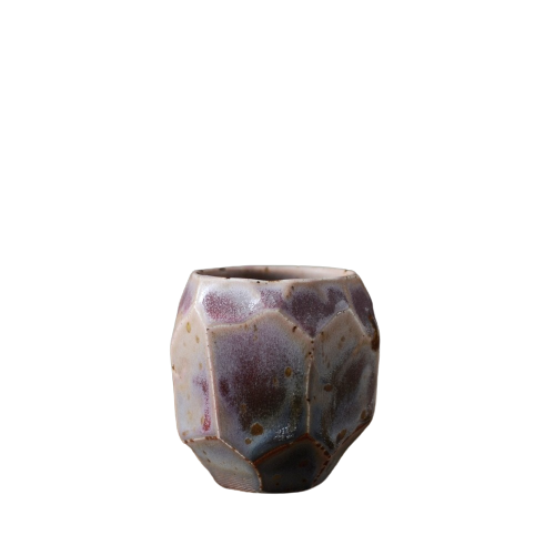 A ceramic tea cup with a textured, speckled surface featuring a mix of purple and brown colors.