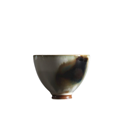 A ceramic art tea cup with a floral pattern and a brown base.