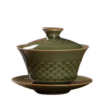 A green and beige ceramic Gai Wan with a fish scale pattern, displayed with its lid and on a matching plate.