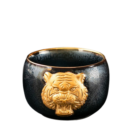 A black ceramic tea cup with a gold tiger symbol on the side.