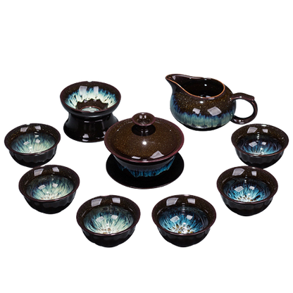 A set of ceramic tea set including six cups, a teapot, and a tea strainer, with a purple and black glaze.