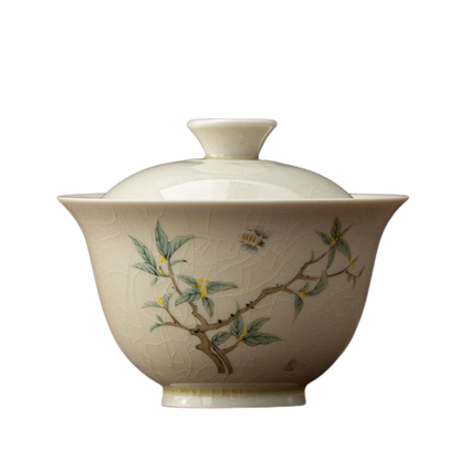 A beige ceramic tea cup with floral and insect patterns, including a prominent bee, indicative of the Osmanthus flower.