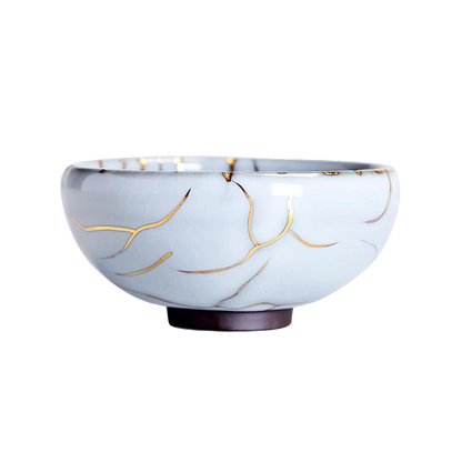 A blue ceramic tea cup with a gold crackle pattern on the side, displayed against a white background.