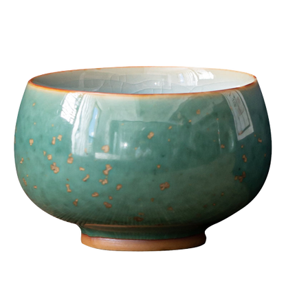 A ceramic tea cup with a green and blue glaze, showing a smooth rim and a textured surface.