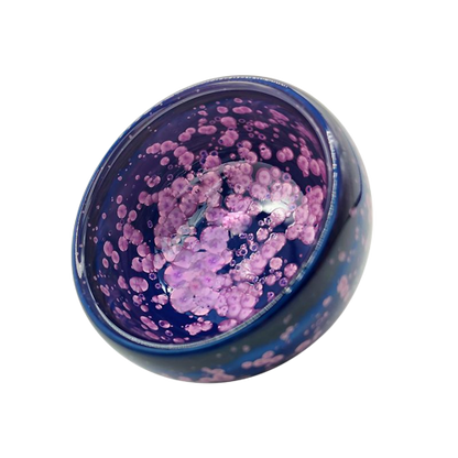 A round, blue and purple tenmoku teacup with a blossom symbol on it.