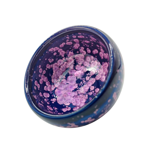 A round, blue and purple tenmoku teacup with a blossom symbol on it.