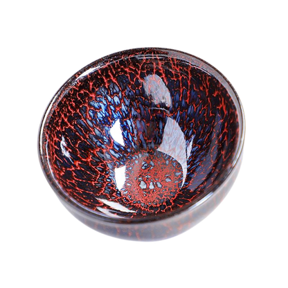 A round, high-temperature ceramic tea cup with a red and blue speckled pattern and a central dark red spot.