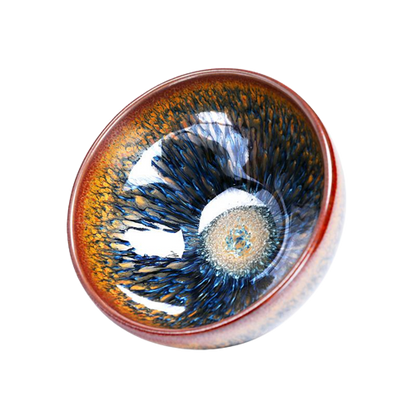 A round ceramic tea cup with a geocentric pattern featuring blue and brown colors and a visible spiral structure in the center.