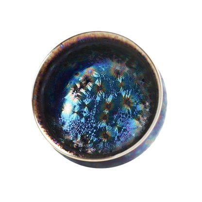 A ceramic tea cup with a blue and black color pattern and a floral design on the side.